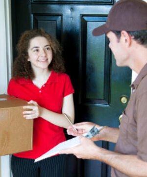 Delivery man brings a package to a customer's door and waits for a signature.